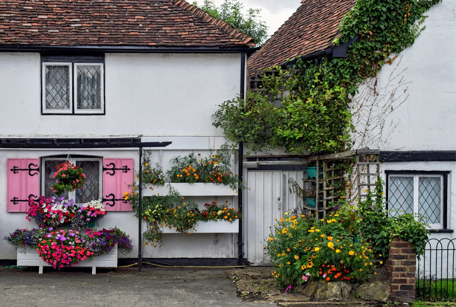 A white cottage with a clay-tiled roof and flowers in Eynsford, Kent